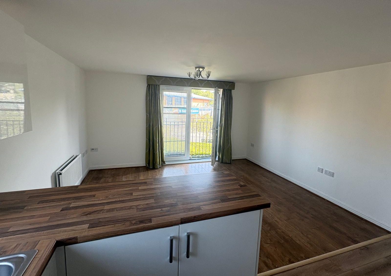 Open-plan kitchen and living area of the completed residential flat, looking towards the balcony doors